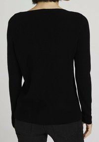 Czarny sweter dzianinowy z długimi rękawami i szerokim, prążkowanym dekoltem. Gładka tekstura i dopasowany krój, zestawiony z ciemnymi dżinsami.