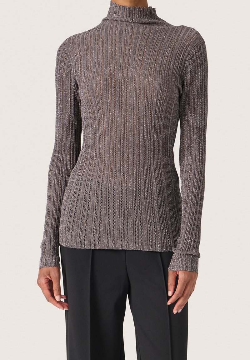 Pull à col roulé côtelé à manches longues, ajusté, de couleur gris métallique, porté avec un pantalon noir, présenté des épaules aux hanches.