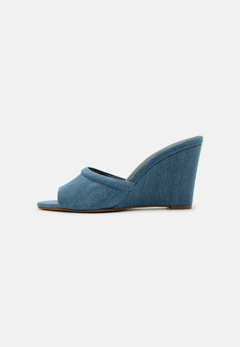 Sandale wedge din denim, cu un design peep-toe, material texturat și toc curbat. Pantoful este de o culoare albastră deschisă solidă.