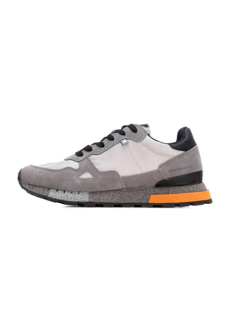 Zapatillas grises con parte superior de ante y tejido, detalles en negro, suela intermedia moteada y suela exterior naranja. Diseño de cordones con punta redondeada.