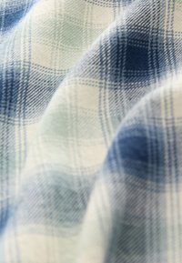 Cotton plaid fabric featuring a pattern of light blue, dark blue, and green squares, with soft texture and subtle woven detailing.