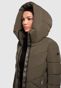 Pehmed roheline jakk kõrge, üle mõõtu kapuutsiga, millel on lukuga suleavamine ja mustad detailid varrukatel ja külgedel.