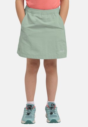 Bambino che indossa una gonna verde menta con vita elastica e scarpe da trekking verde menta con lacci neri e logo Jack Wolfskin.