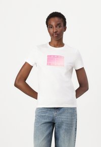 T-shirt en coton blanc avec un design de logo en dégradé rose portant l'inscription "TOMMY JEANS." Manches courtes et encolure ronde classique.