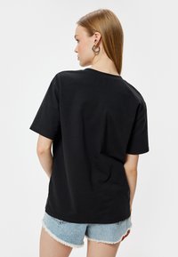 Sort bomulds t-shirt med korte ærmer, afslappet pasform, rund halsudskæring og blød tekstur. Båret med lyseblå denimshorts.