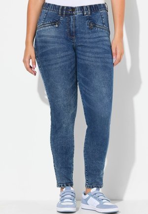 Mid-rise blå denim jeans med forlommelommer med lynlås og ankellange jeans båret med lyseblå og hvide sneakers.