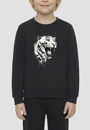 Niño llevando una camiseta de manga larga negra con un gráfico detallado de la cabeza de un tigre blanco rugiente con pintura goteando al frente.