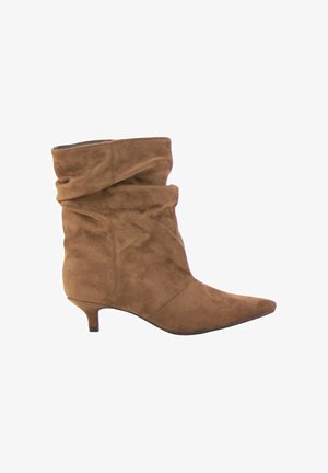 Bota marrón de ante hasta media pantorrilla, con diseño holgado, puntera puntiaguda y tacón bajo estilo kitten, mostrada de perfil sobre fondo blanco.