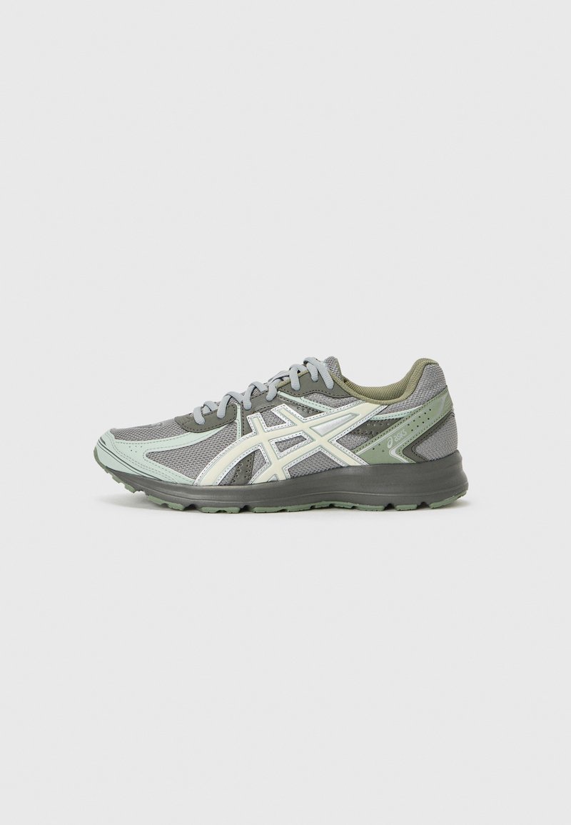 Sport shoe featuring a grey mesh upper with green accents, light reflective details, flat laces, and a textured sole for grip.