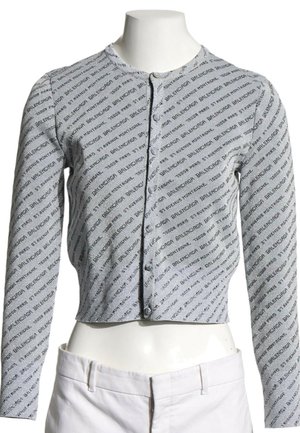 Cardigan gris à manches longues cropped avec motif de texte noir en diagonale et boutons sur le devant, présenté sur un buste de mannequin blanc.