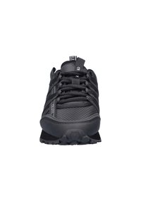 Zwarte sportieve schoen met een gestructureerd oppervlak, gevoerde kraag en vetersluiting. Hexagonaal patroon op de zool en minimalistische designaccenten.