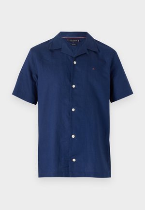 Chemise en lin à manches courtes de couleur marine, avec un col classique, une fermeture à boutons sur le devant et un petit logo sur la poitrine gauche.