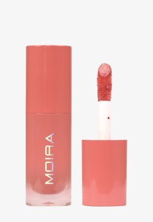 Matta korallinsävyinen nestemäinen huulipuna levitysvipulla, purkissa MOIRA-merkki, yksinkertaista valkoista taustaa vasten.