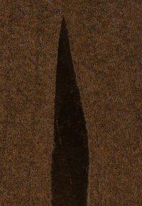 Materiale in feltro marrone con una fessura verticale che rivela un interno scuro. La texture sembra morbida e fibrosa, con una superficie uniforme e ruvida.