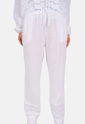 Pantalons blancs, légers et aérés en tissu texturé. Dotés d'une taille à cordon et d'une bordure en dentelle finement ornée à l'ourlet.