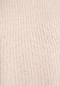 Svetlo béžová žíhaná pletenina s jemnou textúrou a jednotným vzorom, vhodná na odevy alebo textilné aplikácie.