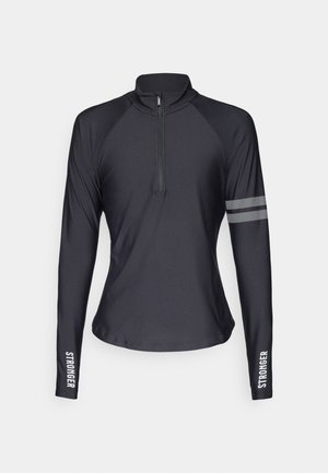 Crni dugodlaki atletski top s polu-zip ovratnikom, s reflektirajućim trakama na lijevoj ruci i tekstom "JACI" na desnoj rukavi.