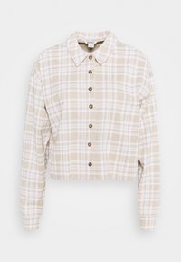 Krátká kostkovaná košile v béžové a bílé barvě. Má límec a zapínání na knoflíky v hnědé barvě. Dlouhé rukávy se zužujícími manžetami.