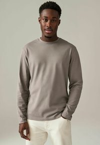 Lange mouwen, crew-neck shirt in lichtgrijze katoen met een gladde textuur, met een losse pasvorm en minimalistisch ontwerp.