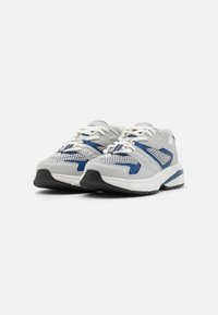 Sport Schuhe mit einem Obermaterial aus Netz und Synthetik in Grau mit blauen Akzenten, strukturiertem Profil und weißen Schnürsenkeln. Abgerundete Zehenkappe und gepolsterte Innensohle.