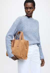 Τσάντα handbag από ταμπά σουέντ με δύο λαβές και κλείσιμο με φερμουάρ. Η τσάντα διαθέτει καθαρό σχεδιασμό με διακριτική υφή και δερμάτινη ετικέτα.