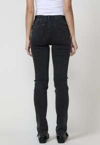 Lieknos juodos džinsus su aukštu liemeniu, turinčius dvi galines kišenes, subtilius siuvinėjimo akcentus ir lygią tekstūrą.