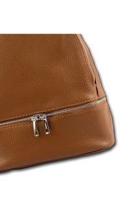Sac en cuir marron à la surface texturée, avec une fermeture éclair en argent en bas et un design à flancs effilés.