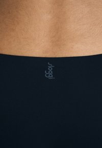 Zwart zwemkledingmateriaal met een gladde textuur. Bevat een subtiele logo op de tailleband. Focus op de achterkant.