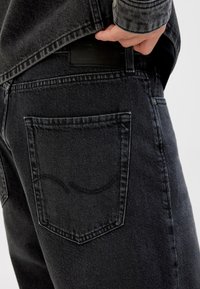 Zwarte denim jeans met een rechte snit, voorzien van een achterzak met een gebogen naaddetail en een leren label op de tailleband.