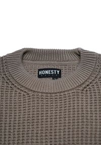 Beige strikket sweater med ribbet rund hals, der har et tekstureret væv. Taggen siger "ÆRLIGHED REGNER," sort med hvid skrift.