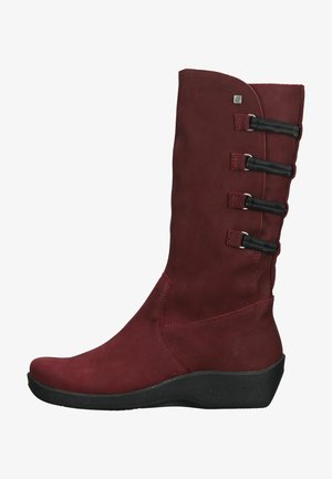 Bottes longues en cuir bordeaux avec une texture lisse, dotées de quatre accents élastiques noirs et d'une semelle en caoutchouc noir à talon compensé bas.