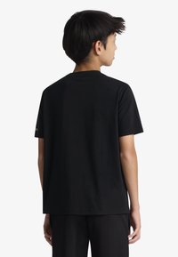 Μαύρο βαμβακερό μπλουζάκι με κοντά μανίκια, στρογγυλή λαιμόκοψη και άνετη εφαρμογή. Χωρίς ορατά σχέδια ή λογότυπα. Απλός και μοντέρνος σχεδιασμός.