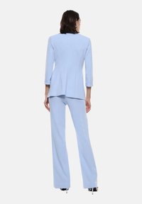 Blazer azzurro chiaro e pantaloni a gamba larga abbinati, realizzati in tessuto liscio. Il blazer presenta maniche a tre quarti e una struttura sartoriale.