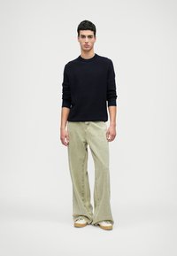 Navy ribbed knit sweater, loose light green jeans, casual sneakers. Simple design, straight leg, visible stitching, and soft texture.