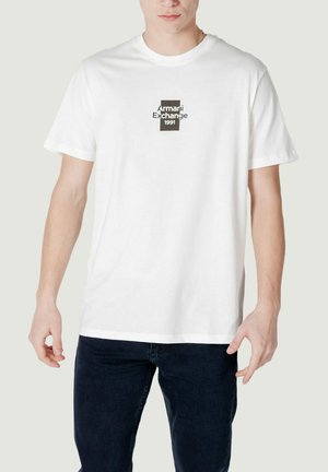 Camiseta de algodón blanca con cuello redondo y mangas cortas, que presenta un logotipo gráfico negro que dice "Armani Exchange 1991" en el centro.