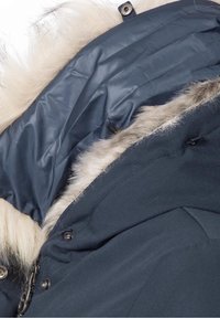 Marineblå parka med hætte i kunstpels, der har et glat inderskud, metaltrykknapper og fremhæver et dobbelt tekstur-design.