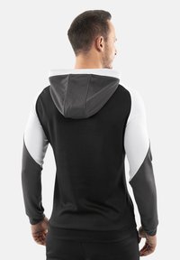 Hoodie noir avec des accents gris et blanc. Comprend une poche frontale, une capuche avec cordon de serrage et des poignets côtelés. Texture lisse avec un design ajusté.