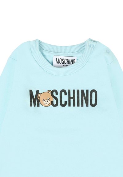 T-shirt pour bébé à manches longues bleu clair avec col côtelé, arborant le texte "MOSCHINO" et un graphique d'ours dans une couleur marron contrastante.