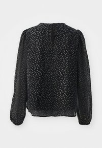 Svart blus med ett lätt, genomskinligt tyg. Har ett spritt ljusgrått mönster, långa puffärmar och en nyckelhålsöppning i ryggen.