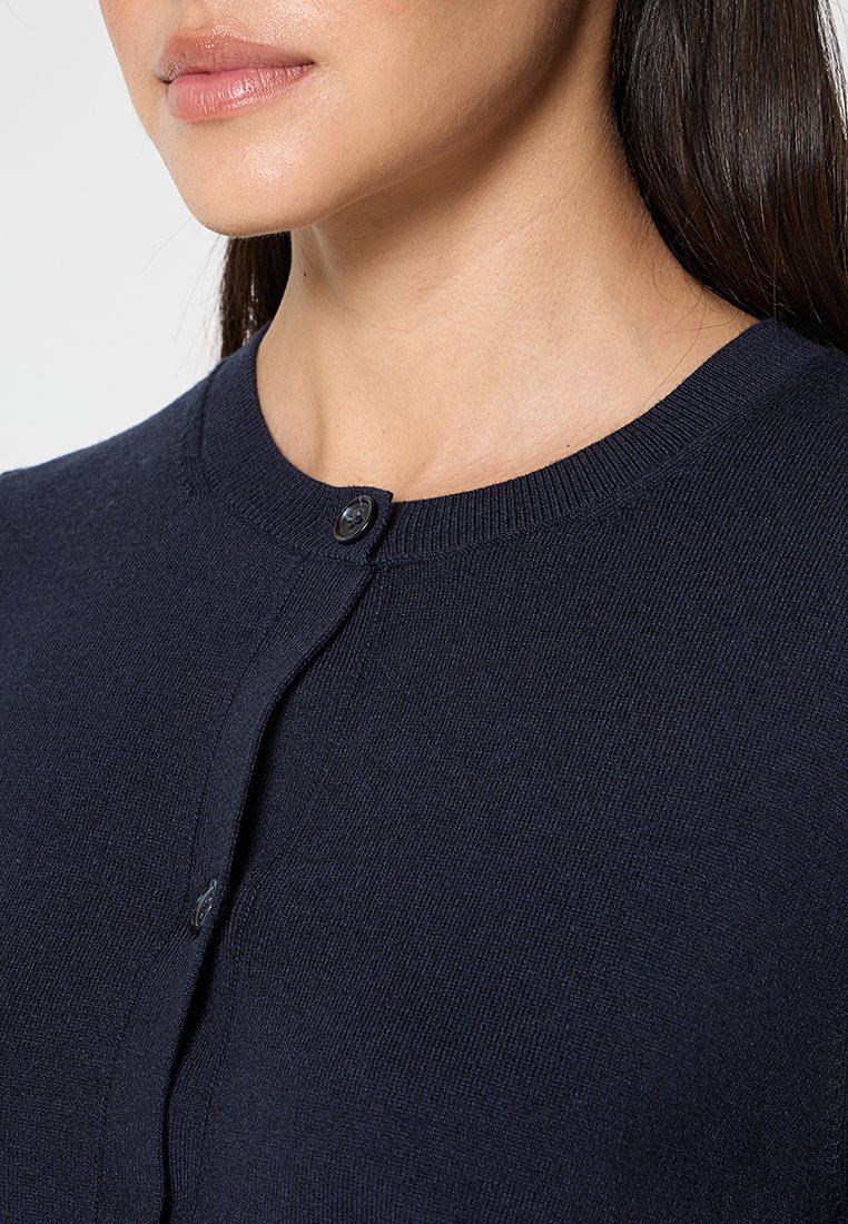 marineblauer Strickcardigan mit rundem Ausschnitt, ausgestattet mit einem einzelnen schwarzen Knopfverschluss und einer glatten Textur.
