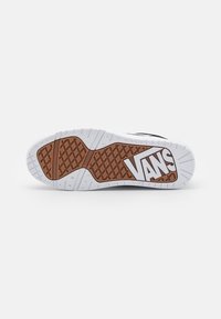 Vans-Sneaker-Sohle mit einem braunen Gummimuster, weißer Zwischensohle mit strukturierter Oberfläche und auffälligem "VANS"-Logo.