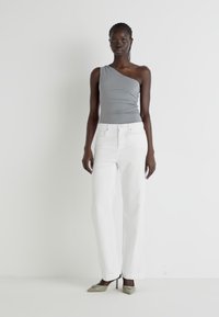Gray one-shoulder top paired with white wide-leg jeans and green heeled shoes. Smooth fabric with minimalist design and tailored fit.