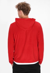 Felpa con cappuccio rossa, dalla texture morbida, maniche lunghe e vestibilità casual. Presenta un design sul retro e uno strato interno bianco all'orlo.