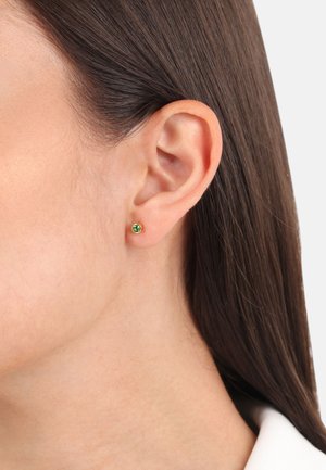 Pendiente de oro con una pequeña gema verde. Forma redonda con superficie lisa, diseño minimalista y acabado pulido.
