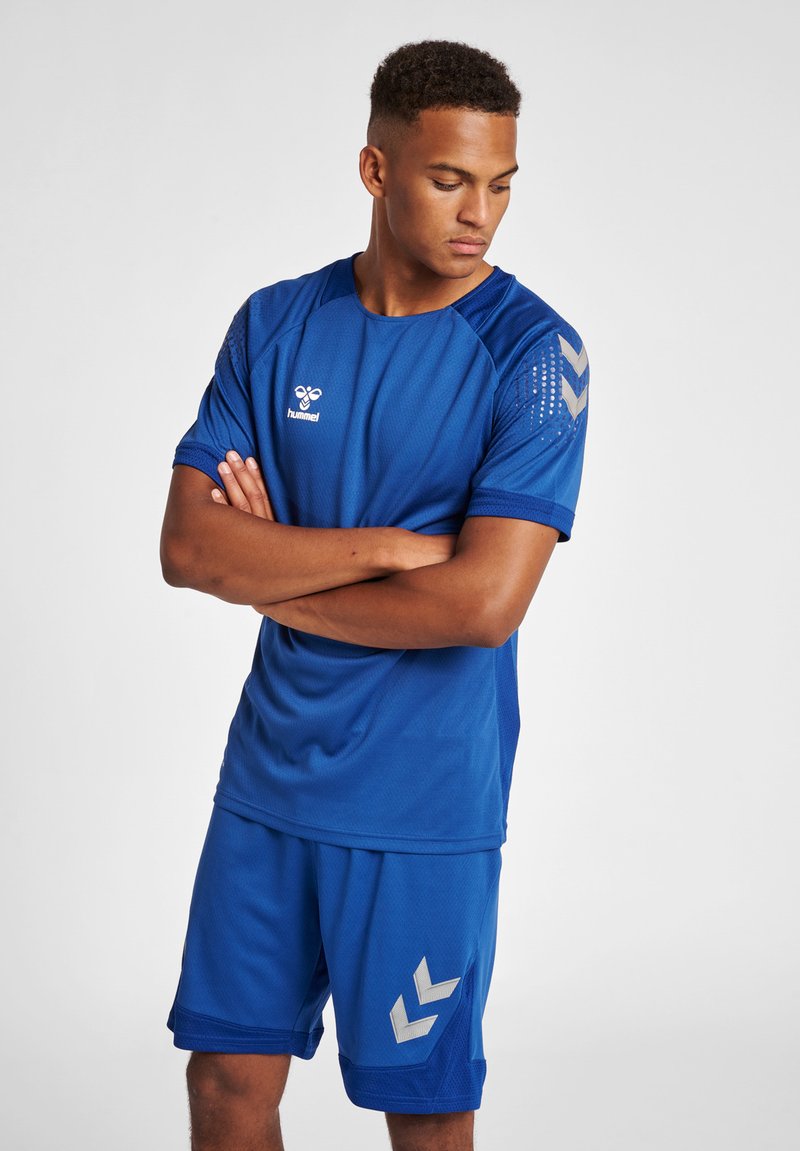 Blauw sportoutfit gemaakt van ademend materiaal. Kenmerkt zich door een t-shirt met korte mouwen en mesh-panelen, en bijpassende shorts met chevron-accenten.