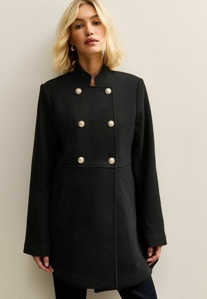 Abrigo de mezcla de lana negro con cuello alto, diseño de doble botonadura, botones en tono dorado y bolsillos laterales; corte relajado y mangas largas.