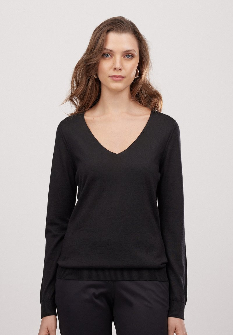 Schwarzer V-Ausschnitt-Pullover mit langen Ärmeln, weicher Textur, figurbetontem Schnitt und geripptem Saum. Einfaches, klassisches Design, das sich gut zum Schichten eignet.
