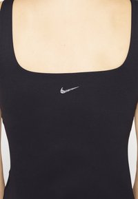 Czarny sportowy top bez rękawów z kwadratowym dekoltem, z małym srebrnym logo Nike na środku. Gładki, elastyczny materiał.