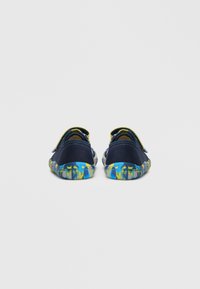 Tumesinised mereväe ujumisjalanõud tekstuurse ülemise kangaga ja eredate sinise-kollase mustriga tallaga; sisaldab libisemisvastast disaini tagumiste aasadega.