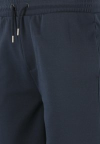 Mörkblå träningsbyxor i ett strukturerat tyg, med elastisk midja och dragsko, perfekta för komfort och passform.